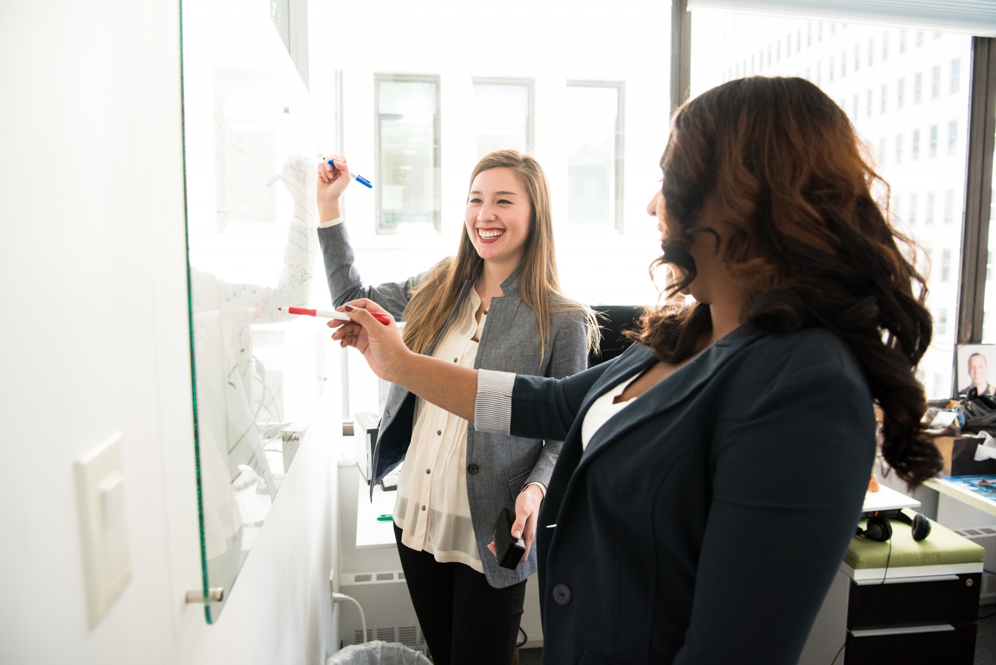 Two women writing on a board