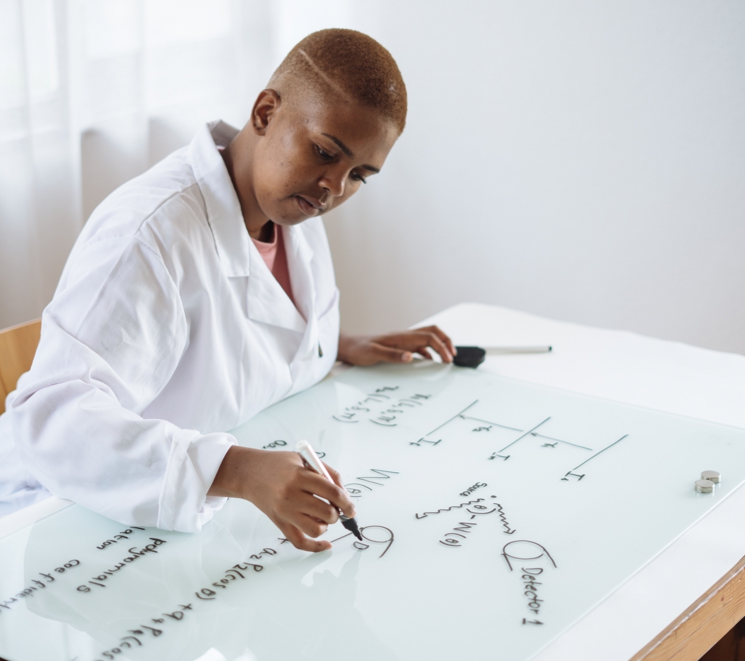 African-American woman writing on a clear board