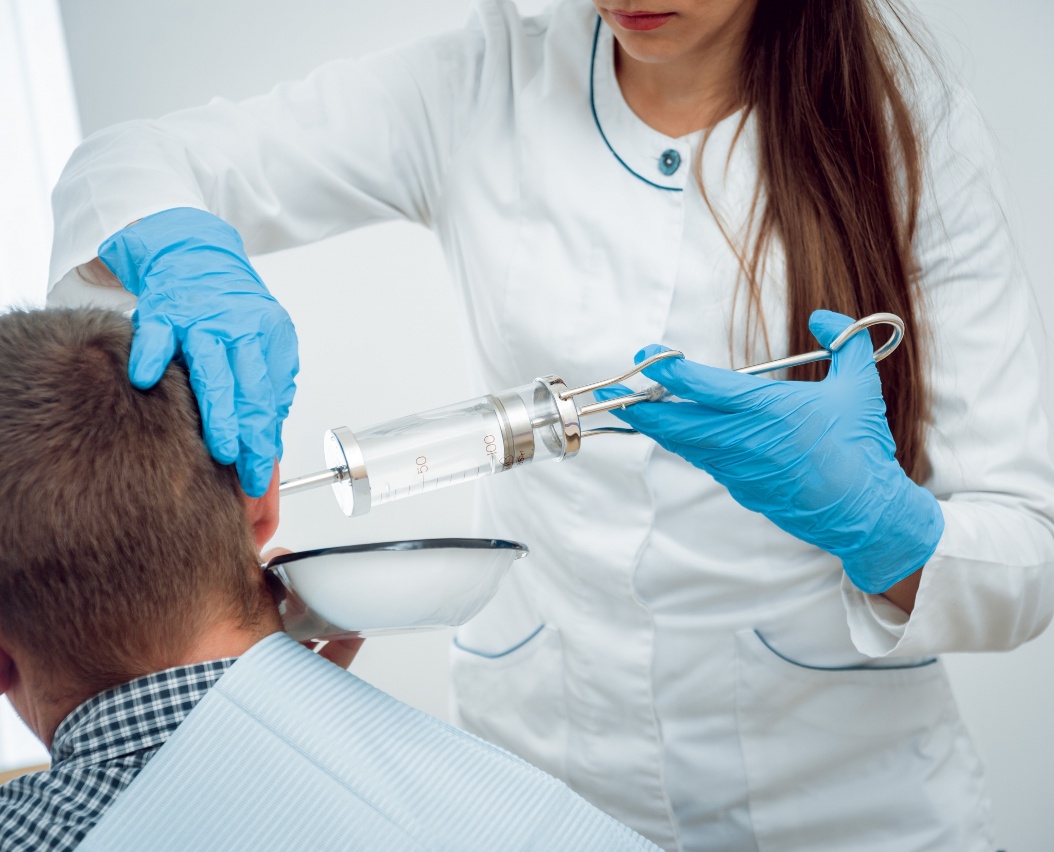 Nurse irrigating a man's ear