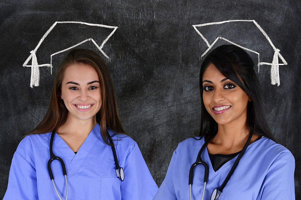 Medical graduates smiling in front of a blackboard