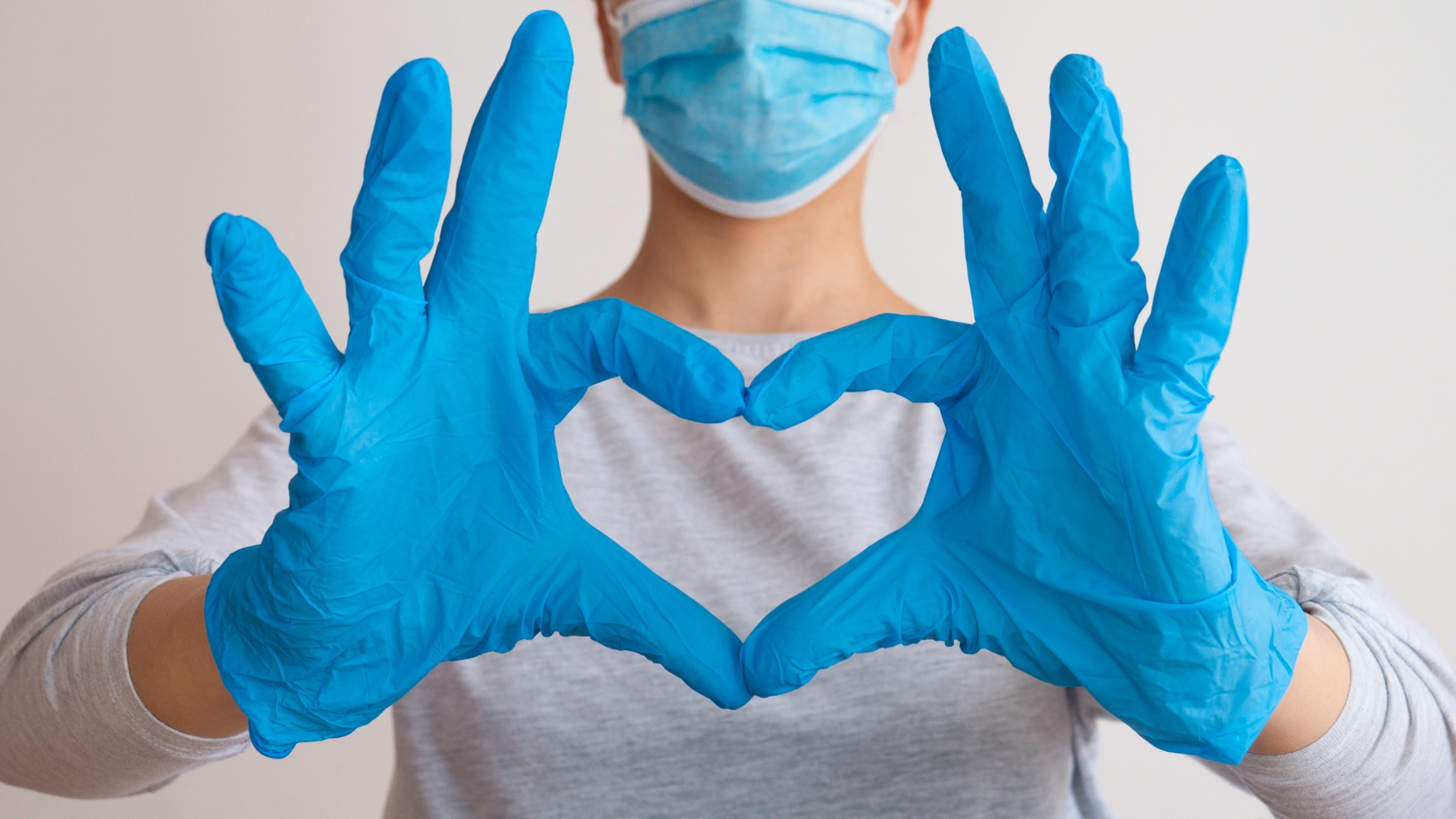 Woman in a medical mask making a heart sign
