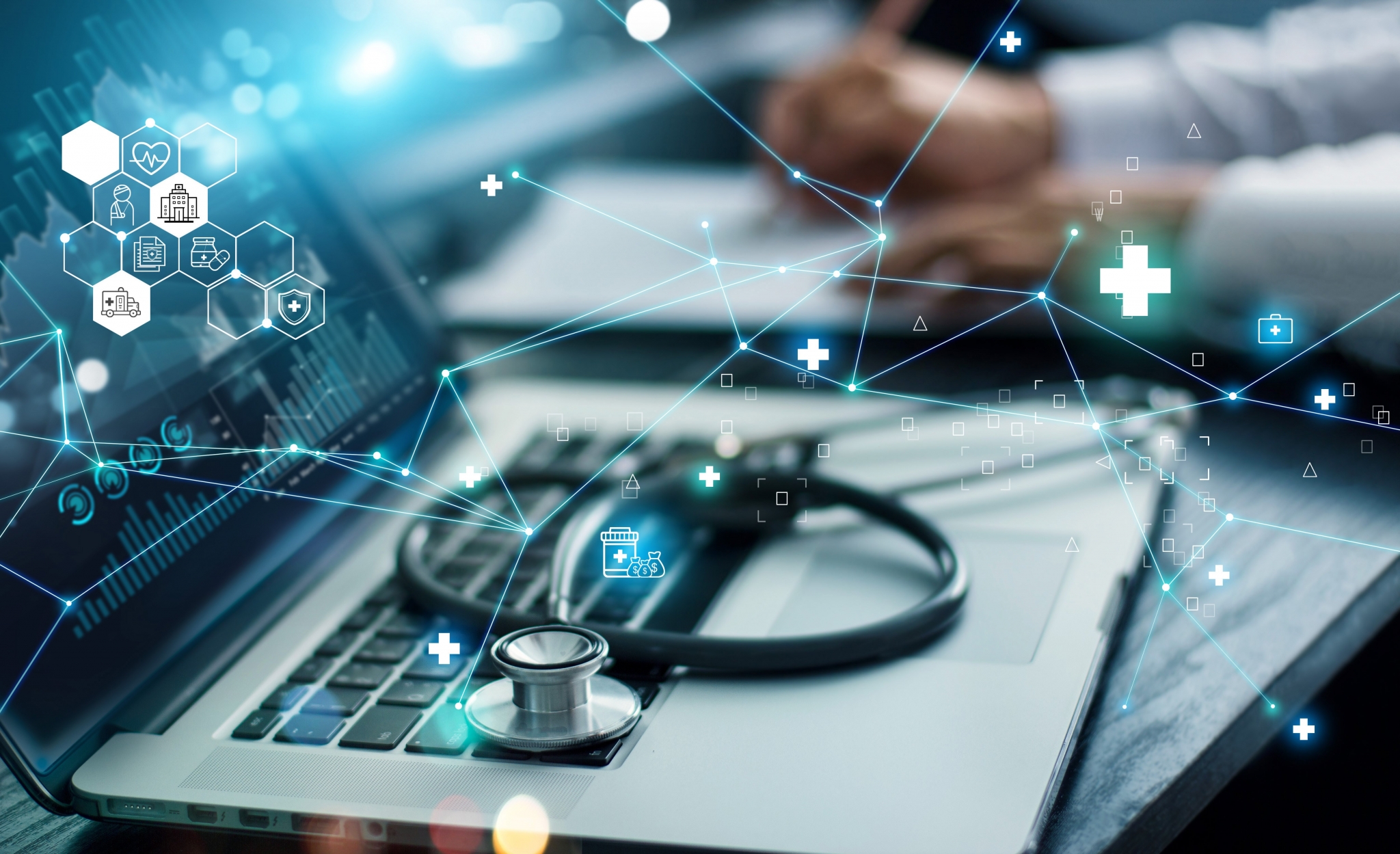 Stethoscope laying ontop of laptop keyboard while person is writing on papers with a pen