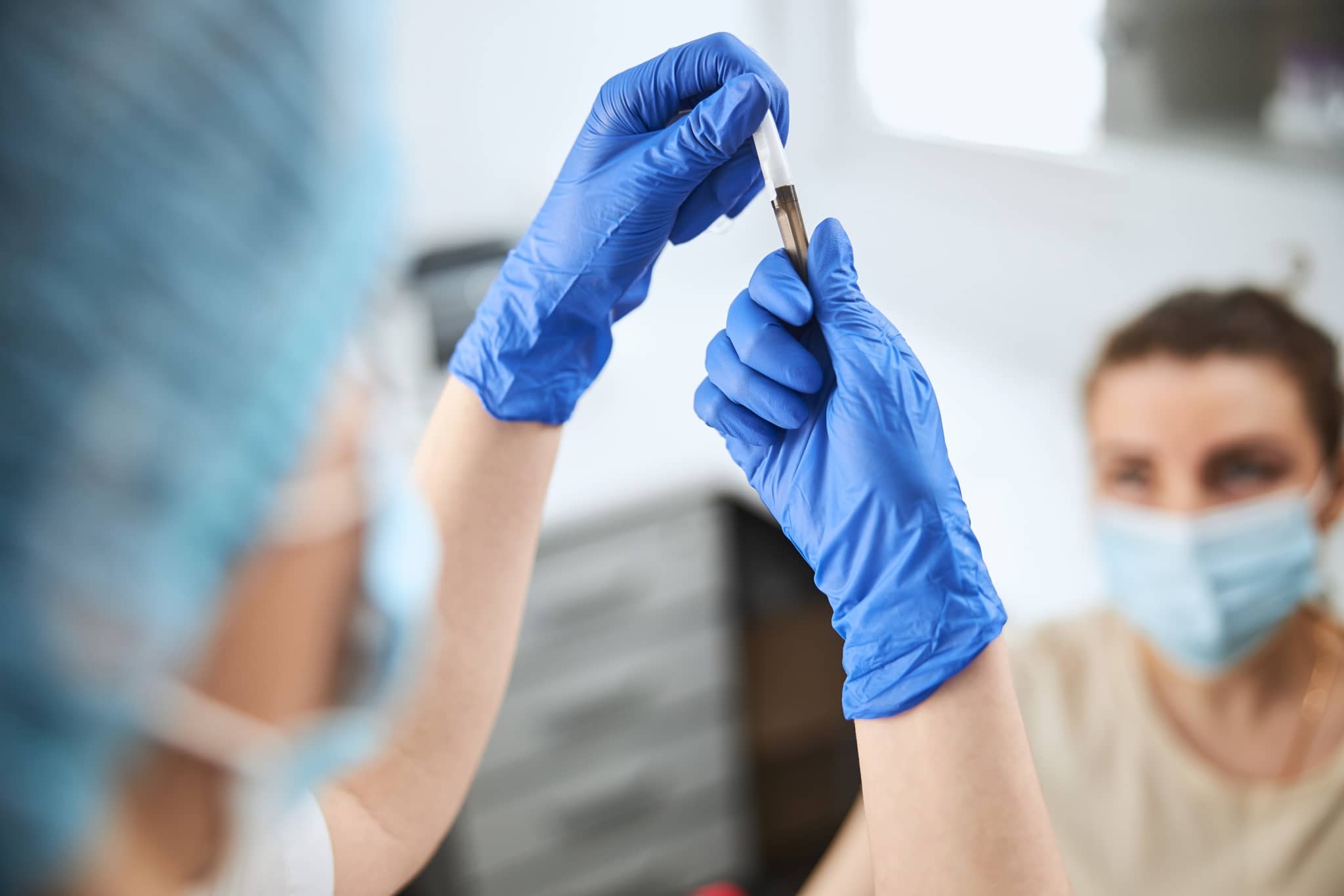 Gloved hands holding a syringe