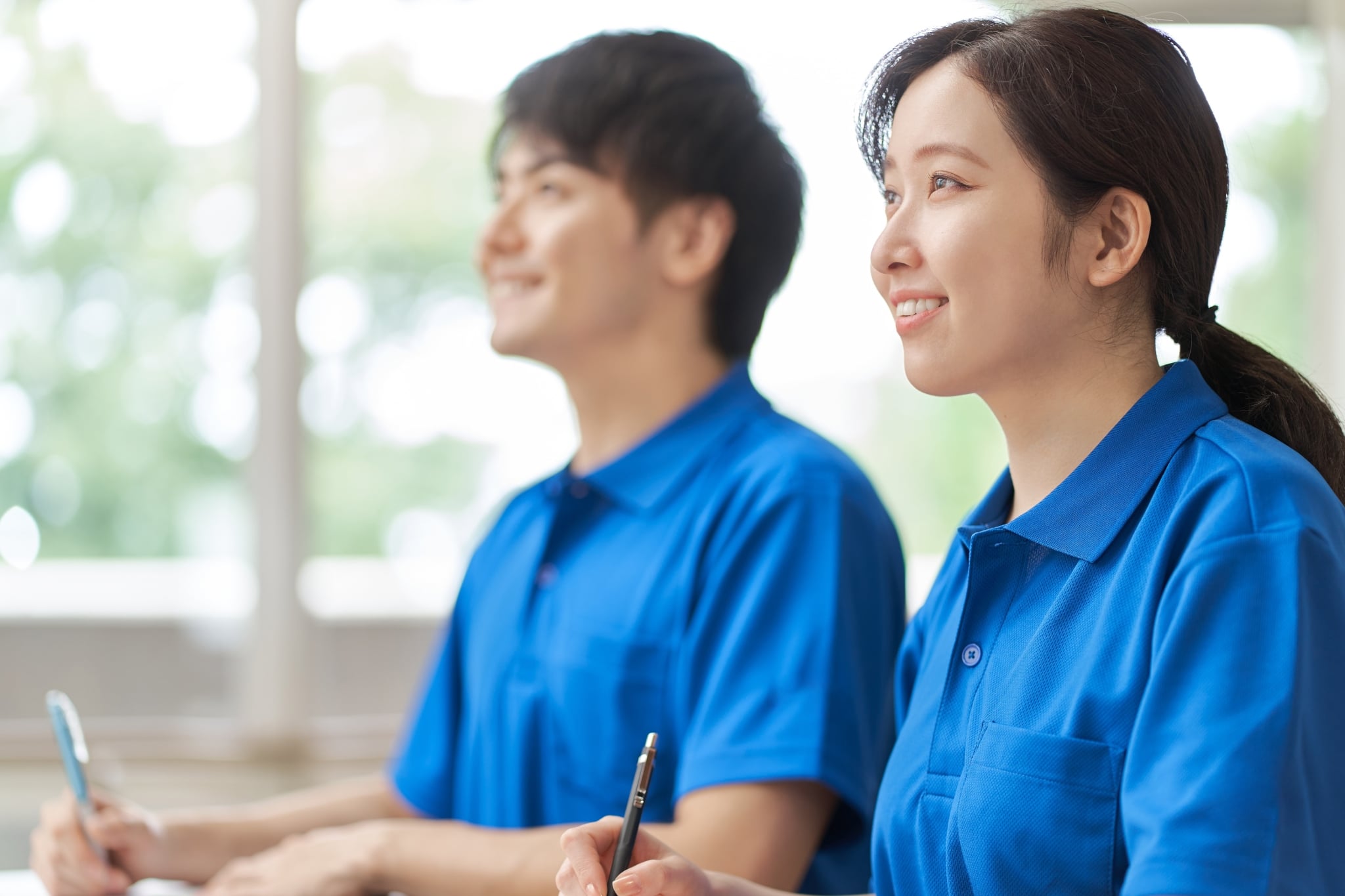 Two smiling Asian nurses taking notes