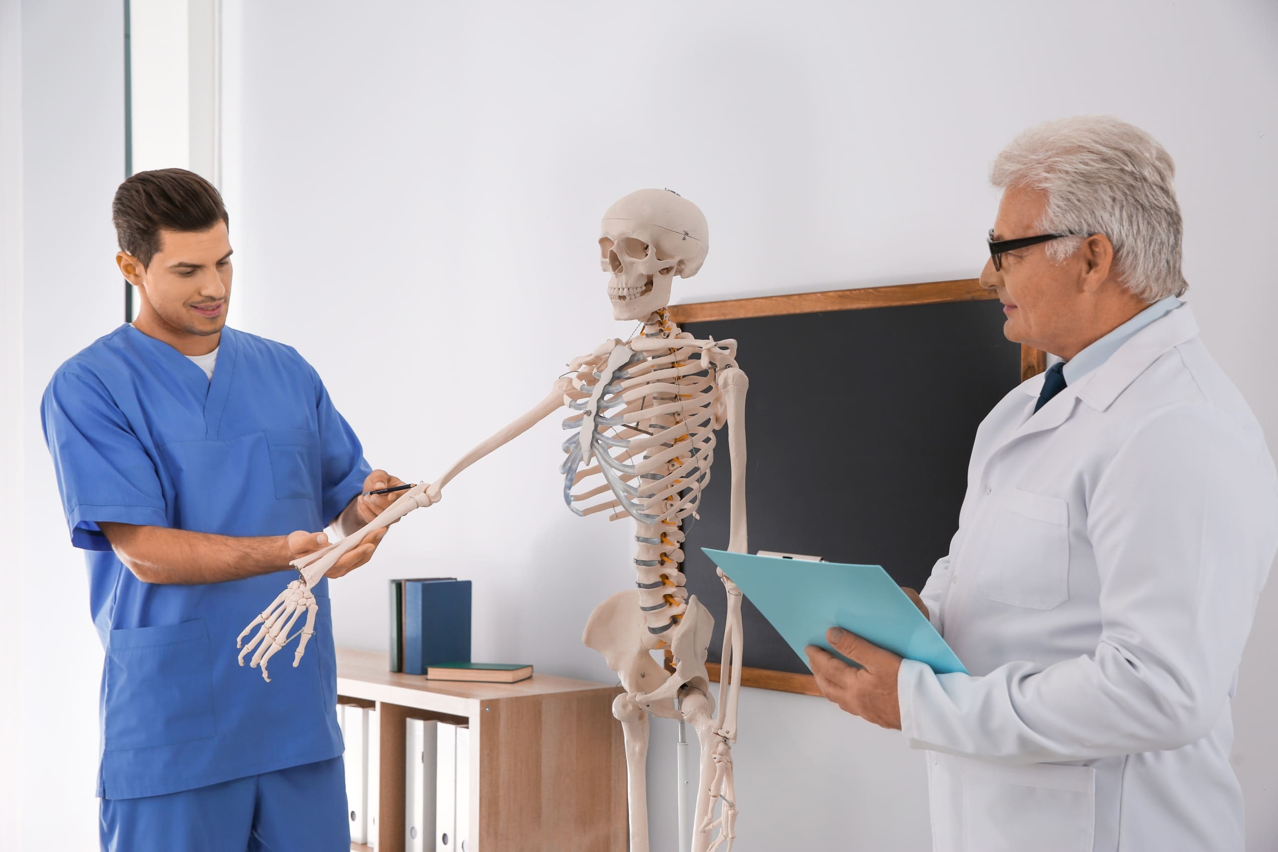 Medical student and professor studying a human skeleton