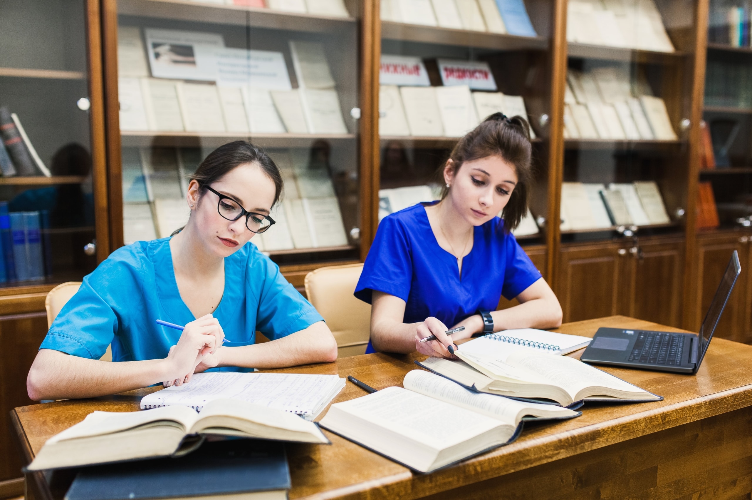 Medical students studying with textbooks and laptops