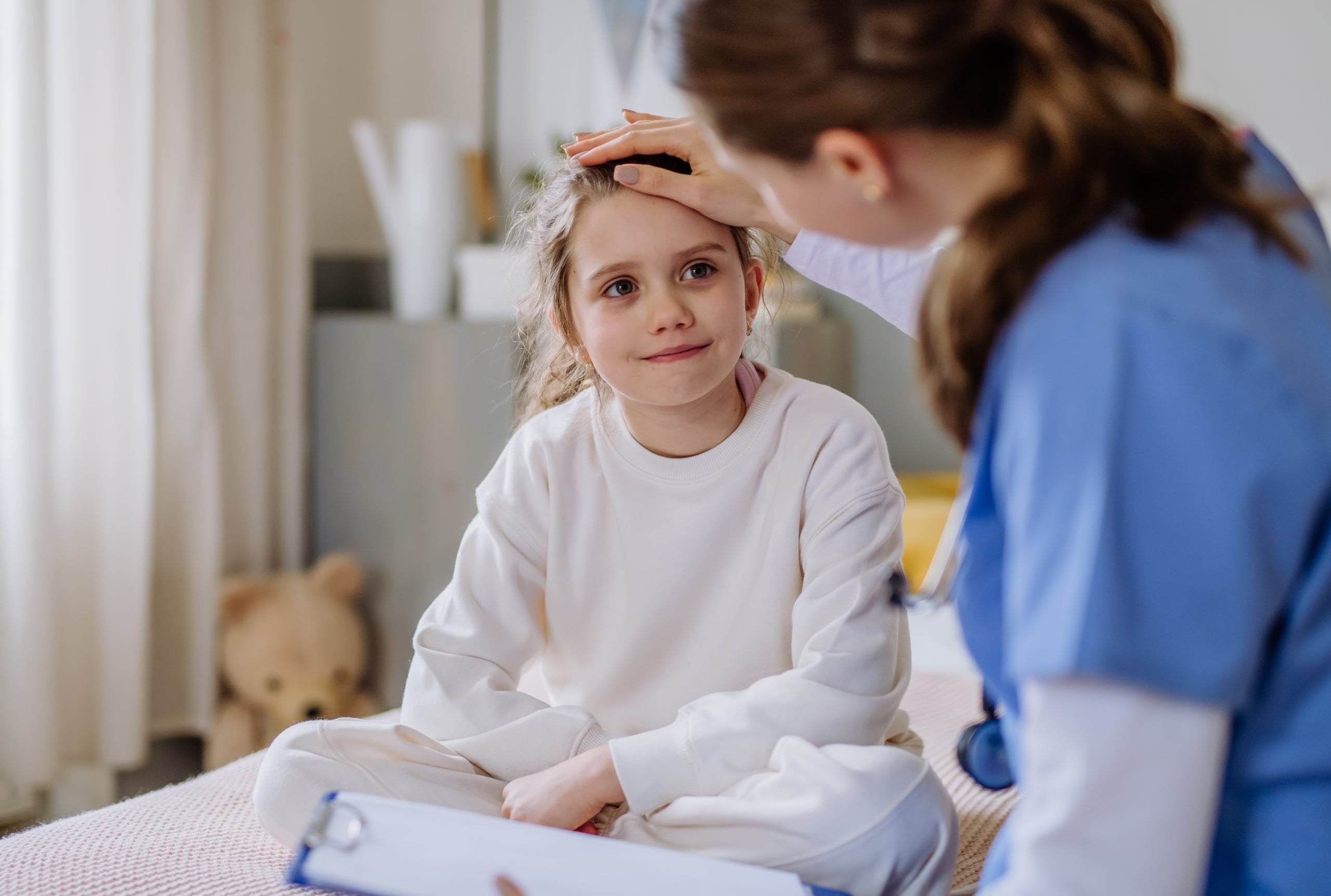 Female nurse consoling a young girl in a hospital room