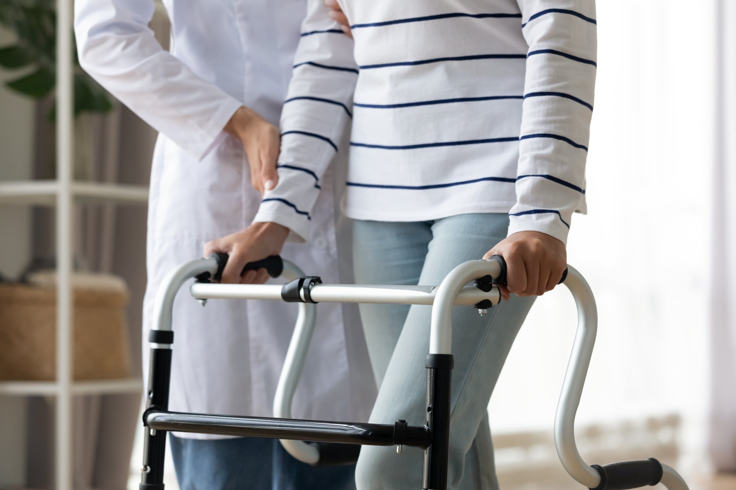 Close up of a medical professional helping a patient use a walker