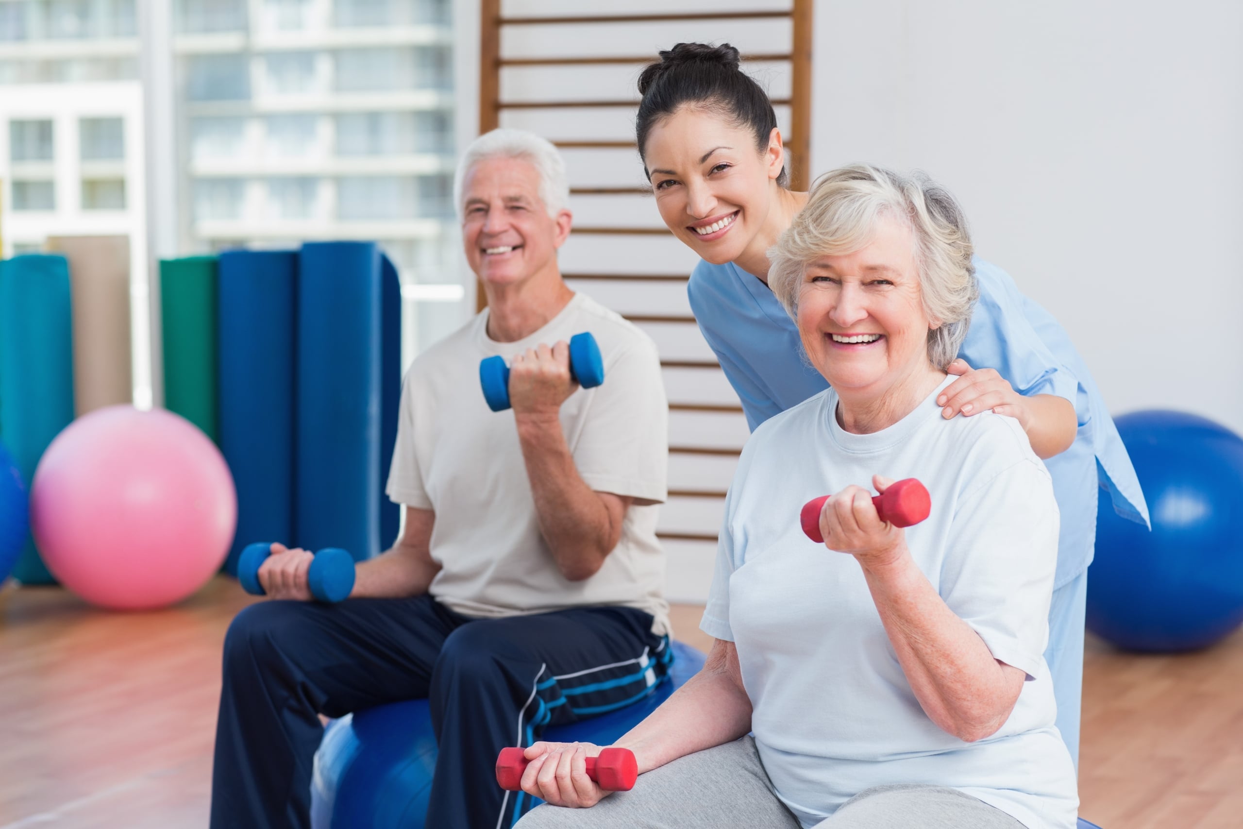 Physical therapy professional helping older patients lift weights