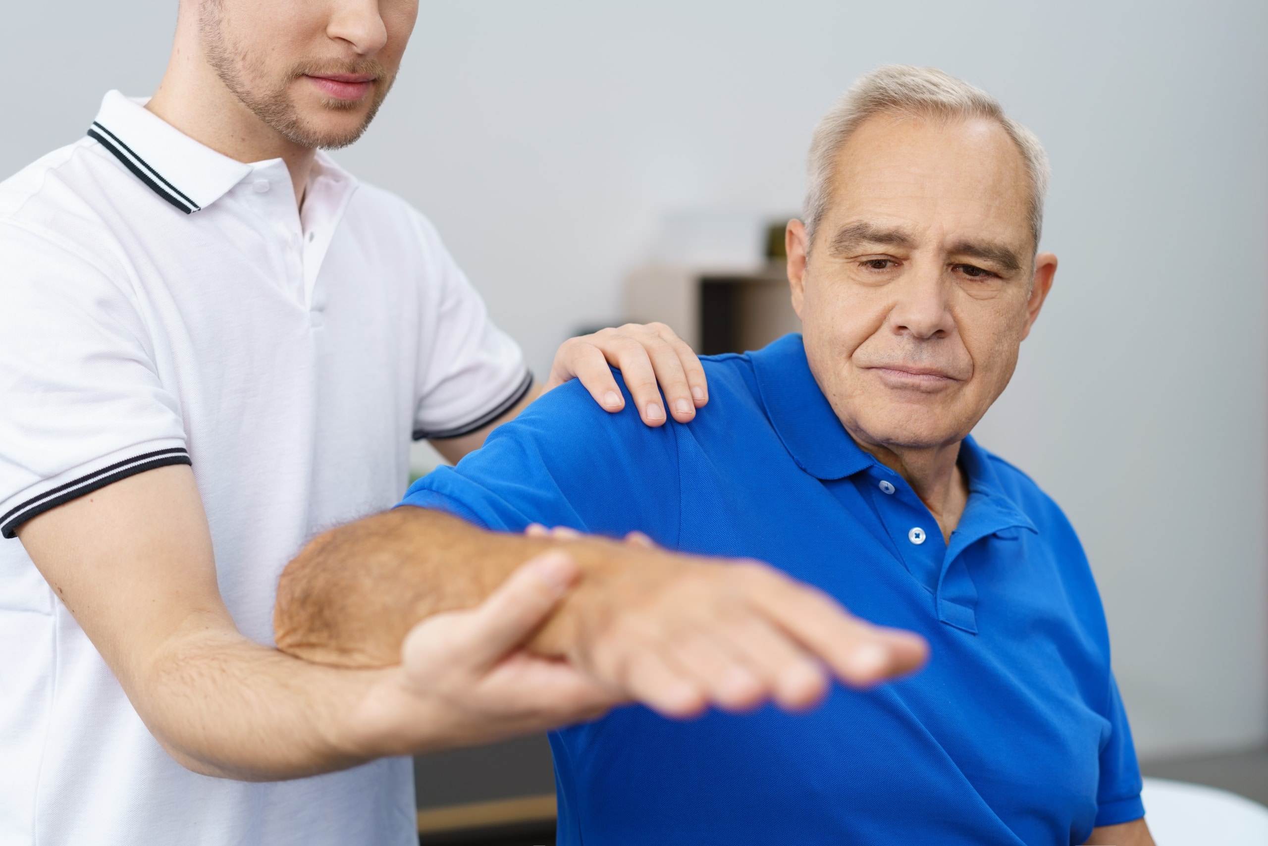 Close up of a physical therapy professional manipulating an older man's arm