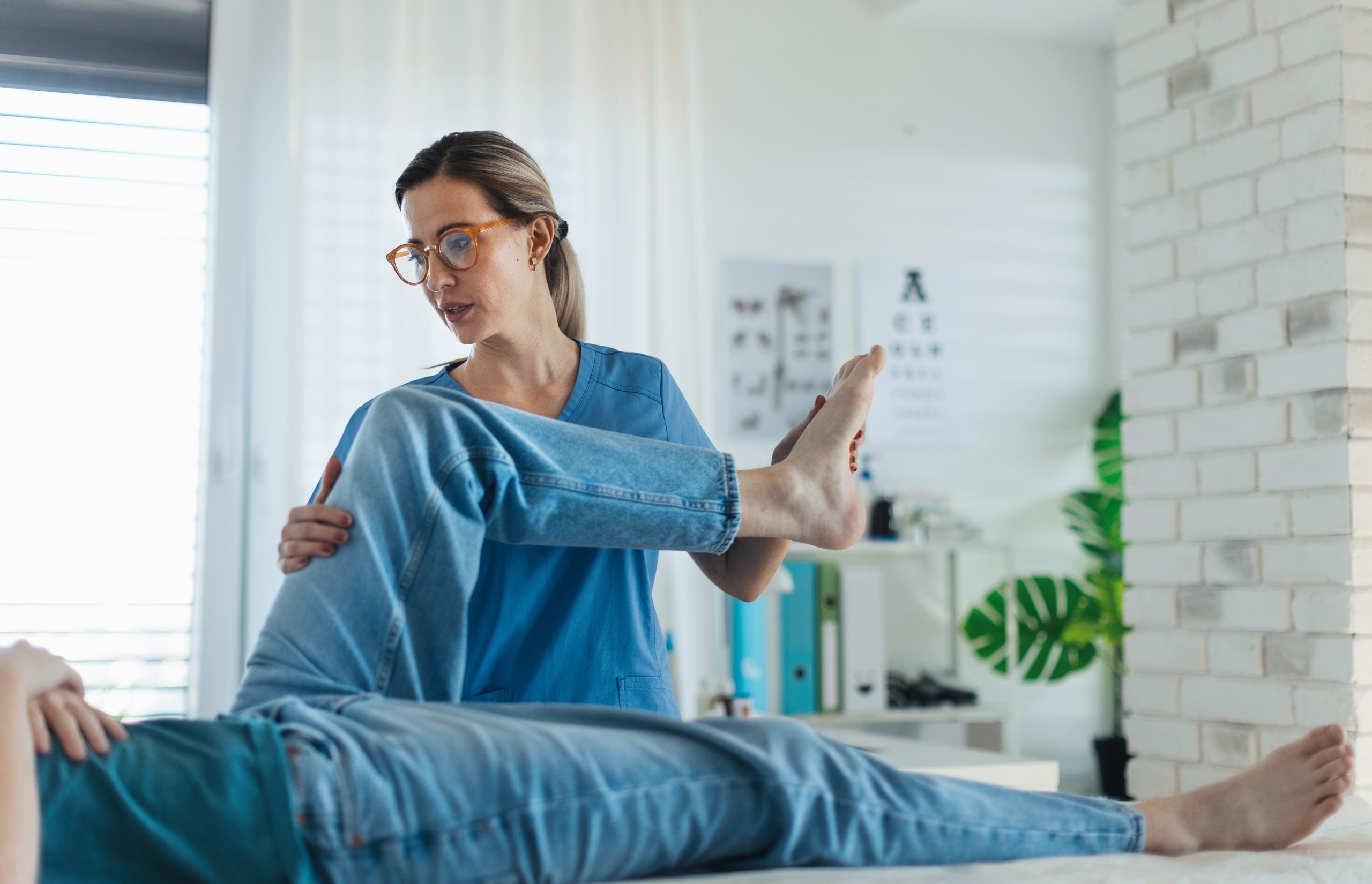 Female physical therapy professional helping a patient stretch