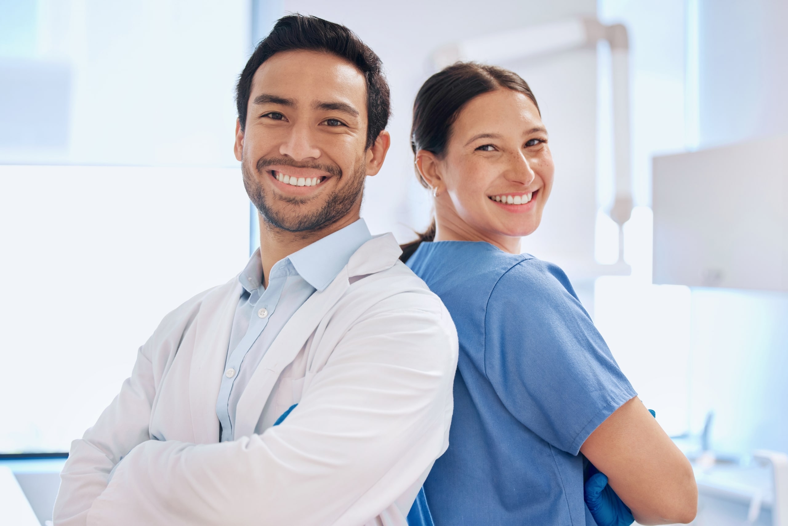 Two medical professionals standing back to back with their arms crossed