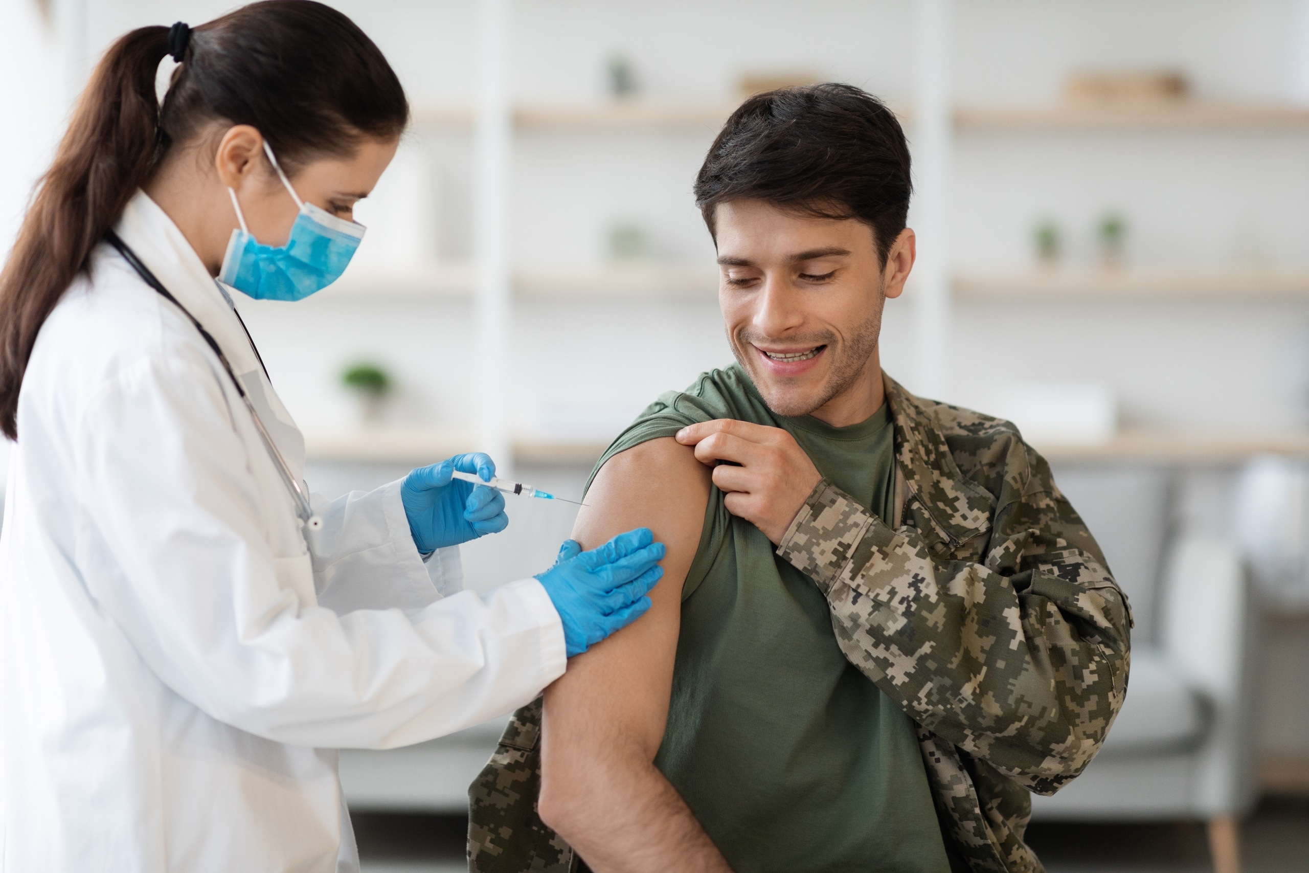 Cheerful man in a military uniform receiving a vaccination