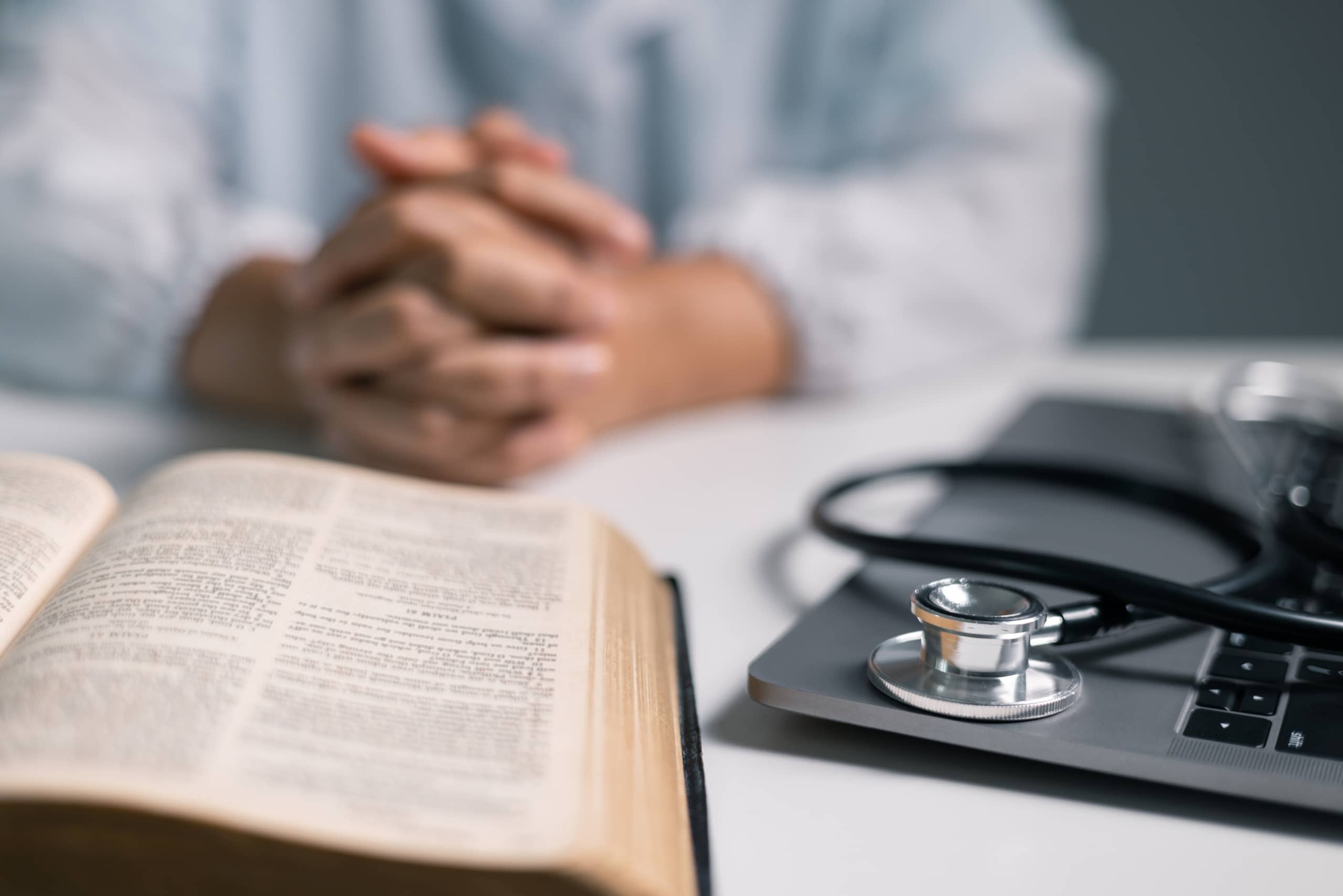 Medical professional with clasped hands and a textbook