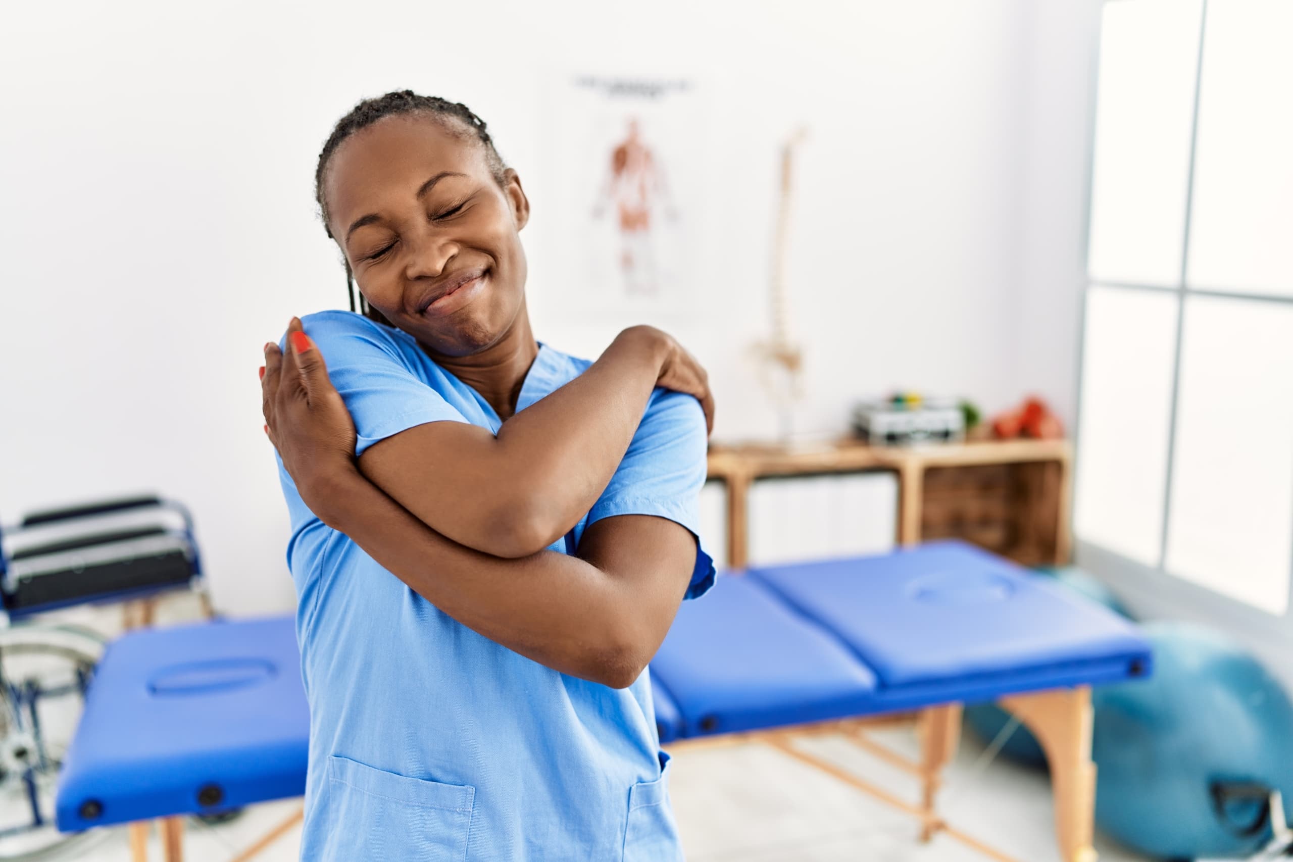 Physical therapist assistant hugging herself in a clinic