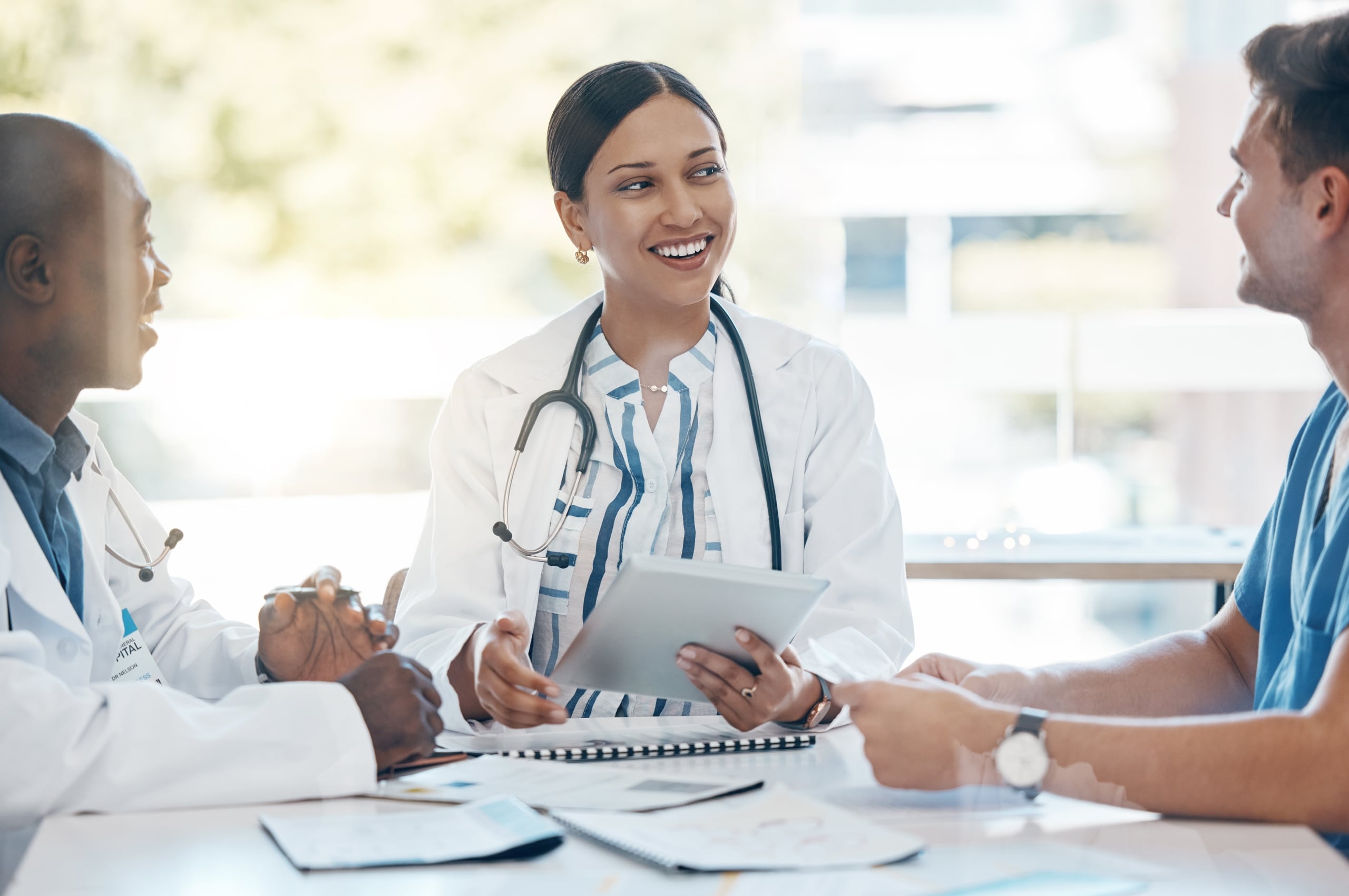 Diverse medical professionals using a tablet in a meeting