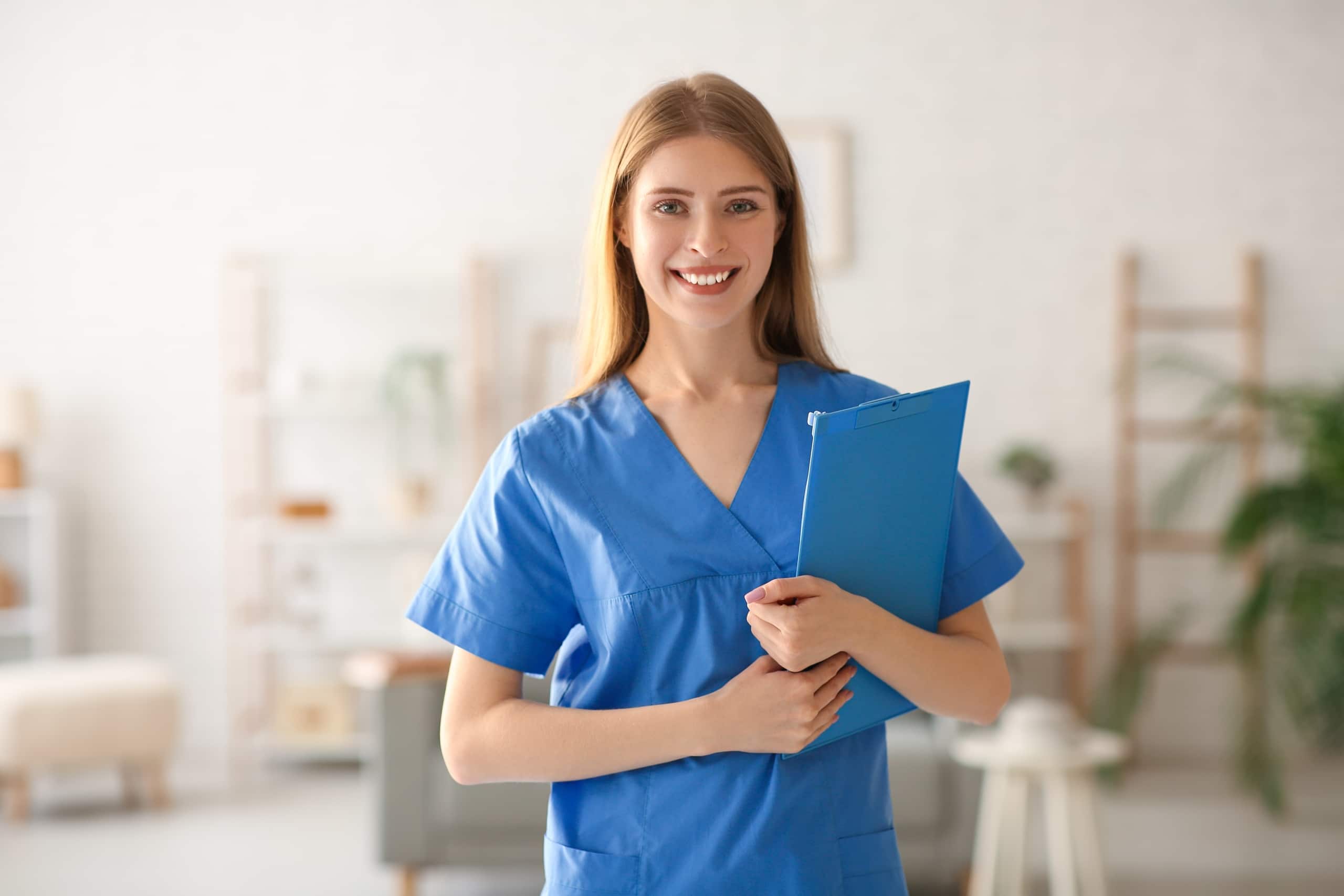 Blonde medical professional in scrubs with a clipboard