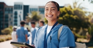 Happy nursing student standing outside with a tablet