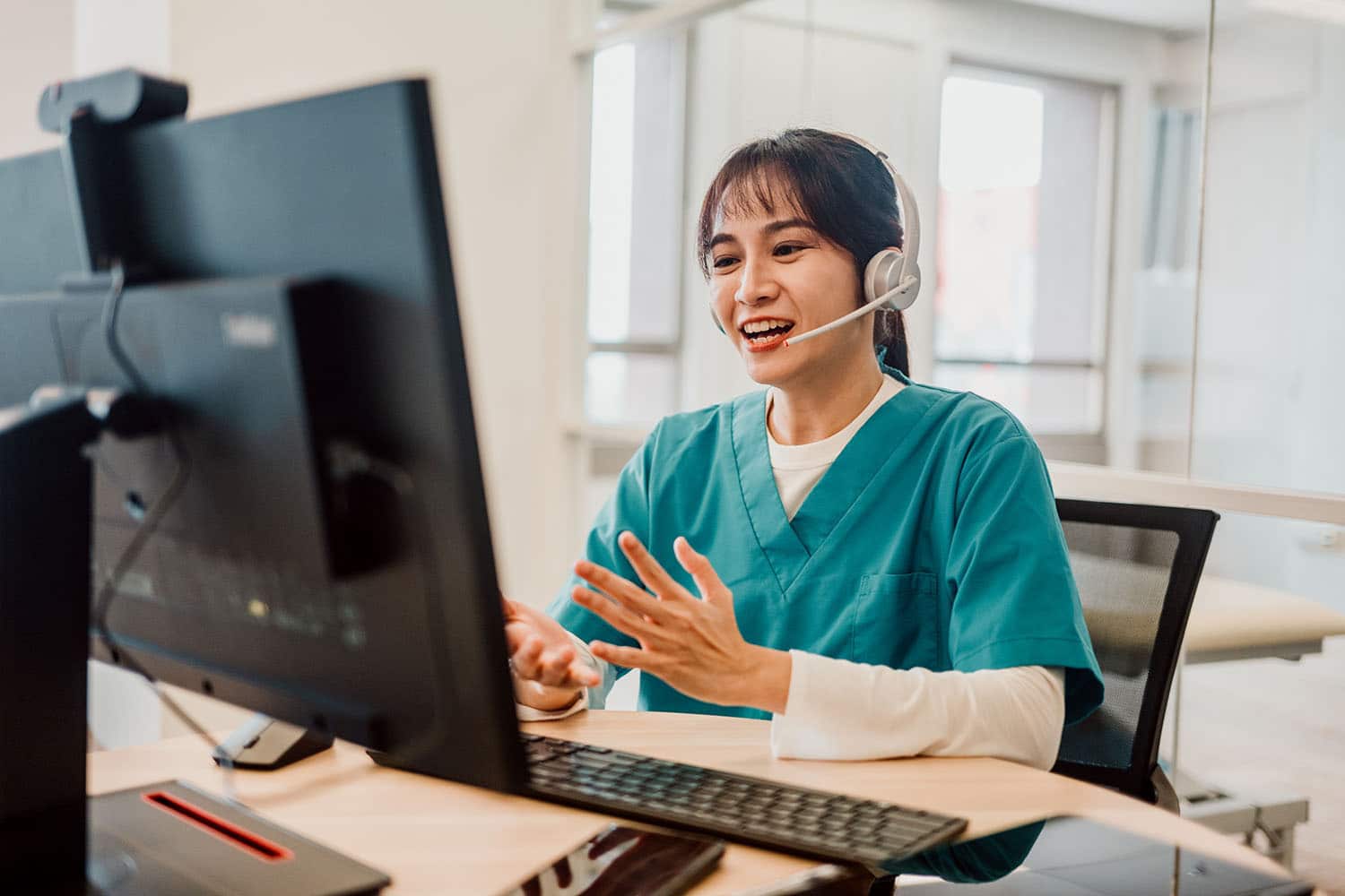 Asian medical professional using a desktop and headset