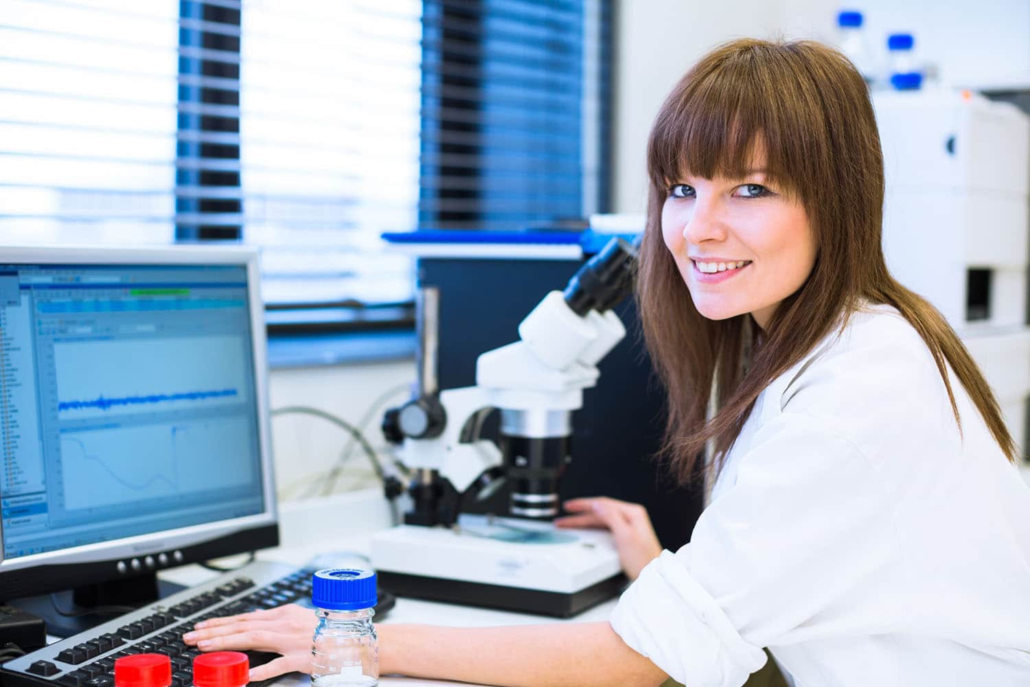 Young woman using a computer and laboratory equipment