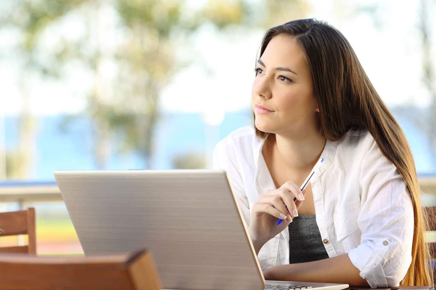 Young woman using a laptop while deep in thought